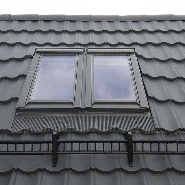 Et tak av svarte, bølgete takplater og taksikring med et nytt installert takvindu 