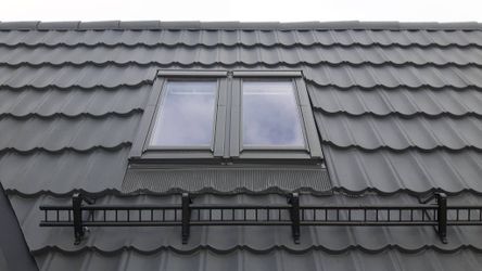 Et tak av svarte, bølgete takplater og taksikring med et nytt installert takvindu 