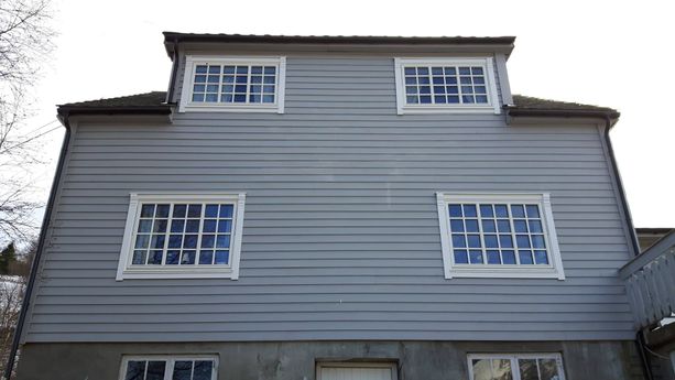 Grått hus med ny uskiftede vindu med detaljer på hvite vinduskarmer