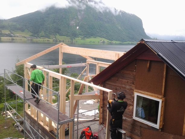 To ansatte som snekrer i prosessen med å bygge et tilbygg til en hytte.