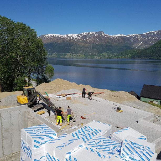 Startfasen med å bygge en hytte hvor bare grunnmuren er lagt og noen få vegger er satt opp med utsikt over en fjord