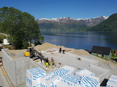 Startfasen med å bygge en hytte hvor bare grunnmuren er lagt og noen få vegger er satt opp med utsikt over en fjord