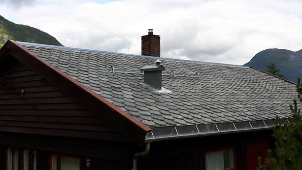 Nytt skifertak på et hus med to piper som stikker opp fra taket