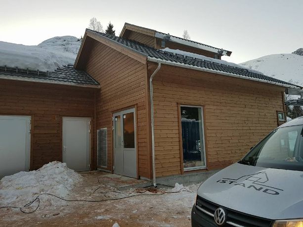Et ferdig tilbygg på et hus med snø på takene, moderne vindu og en firmabil i forgrunnen