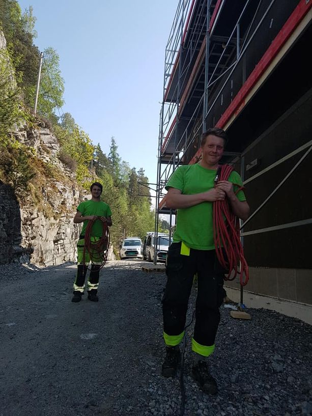 To ansatte som bærer ting inn i et hus som holder på å bli bygd opp