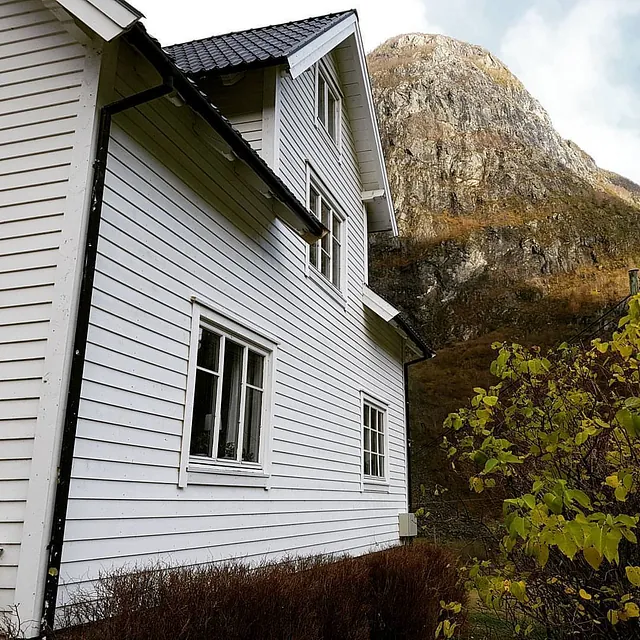 Et hvitt his med ny fasade og etterisolering med et fjell i bakgrunnen 