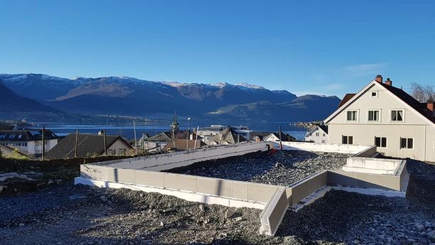 Støping av grunnmur til et hus i et boligfelt hvor man ser ut over en fjord og fjell 