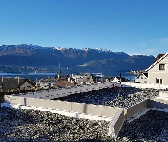 Støping av grunnmur til et hus i et boligfelt hvor man ser ut over en fjord og fjell 
