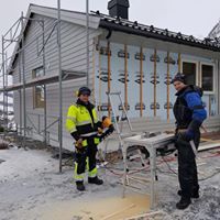 To ansatte som arbeider med etterisolering til et hus som har stilas satt opp rundt seg