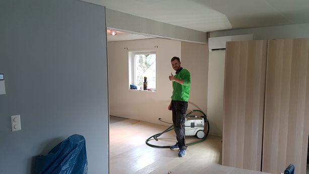 En ansatt som viser tommel opp i en nylig ferdig oppusset og utvidet lys stue