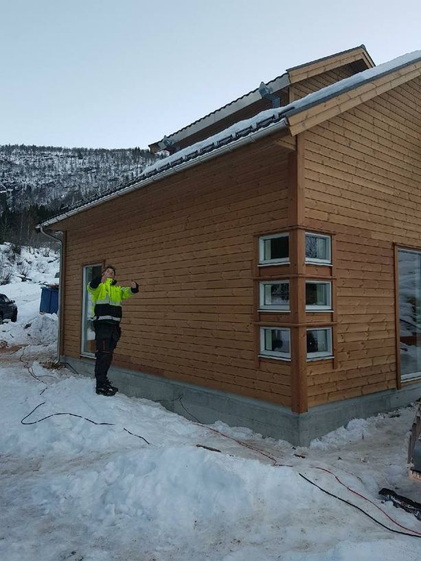 En ansatt som poserer fremfor et ferdig tilbygg med snø på bakken
