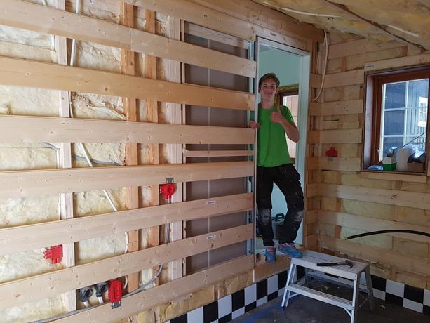 En ansatt som gir tommelen opp på et prosjekt hvor de totalrehabiliterer, etterisolering, ventilasjonsanlegg samt nye vinduer på innsiden av et hus