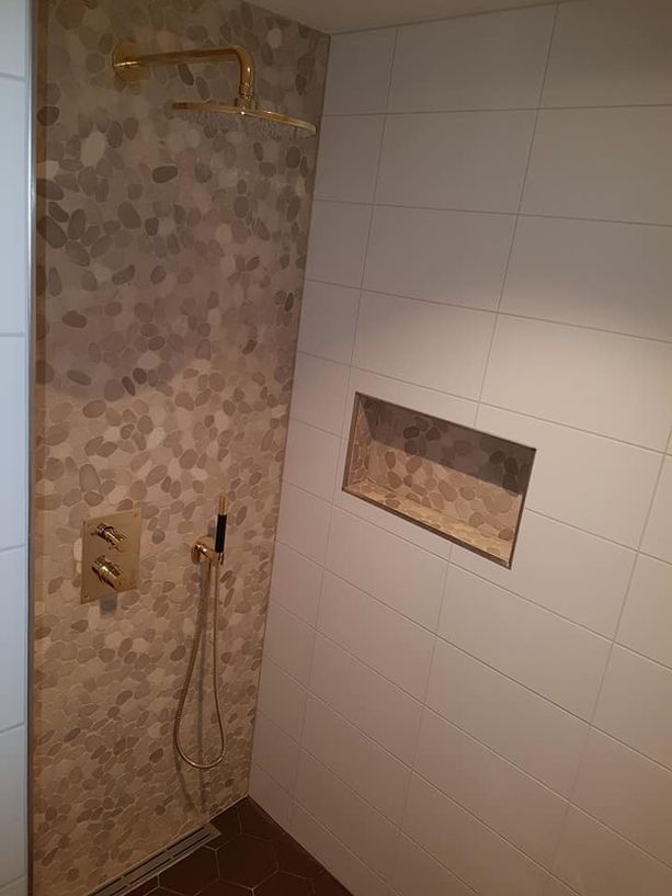 Dusj med vannfall og vanlig dusjhode, innebygd hylle og flislagte vegger og gulv