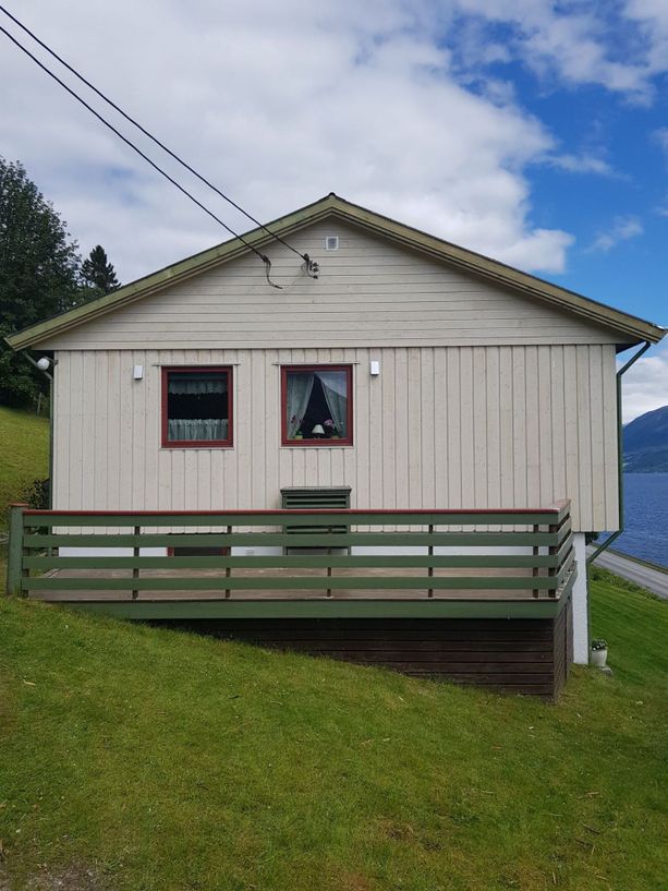 Et lite hus som står i en bakke med en helt ny balkong